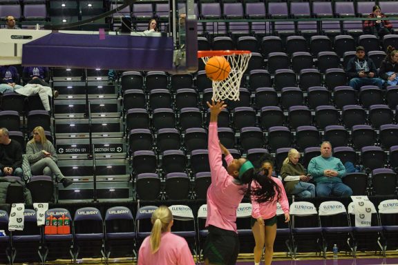 Female basketball player shoots a ball at the hoop during warm-ups.